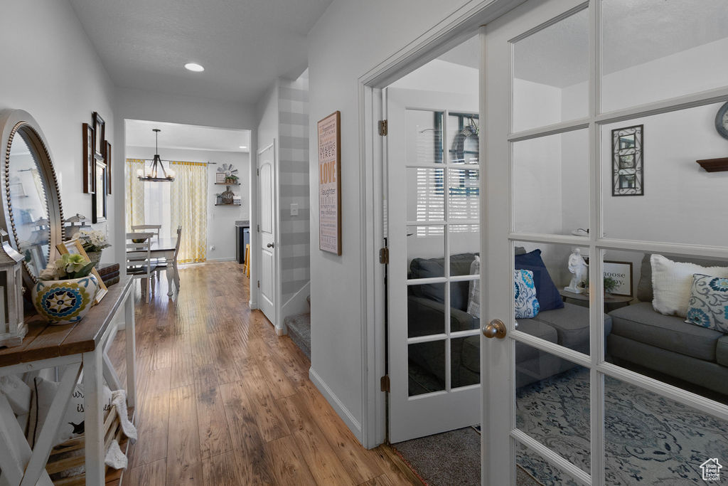 Hallway with a chandelier, wood finished floors, baseboards, and recessed lighting