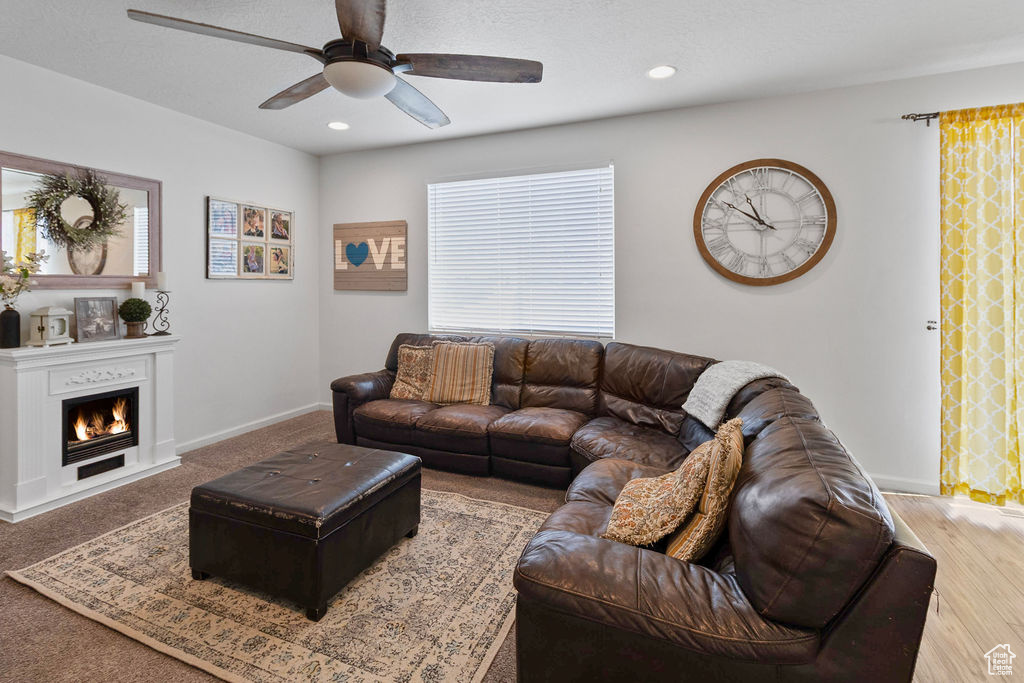 Living room with ceiling fan, baseboards, a lit fireplace, and recessed lighting