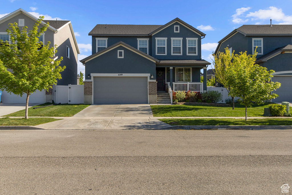 View of front of home featuring driveway, brick siding, a gate, a porch, and an attached garage
