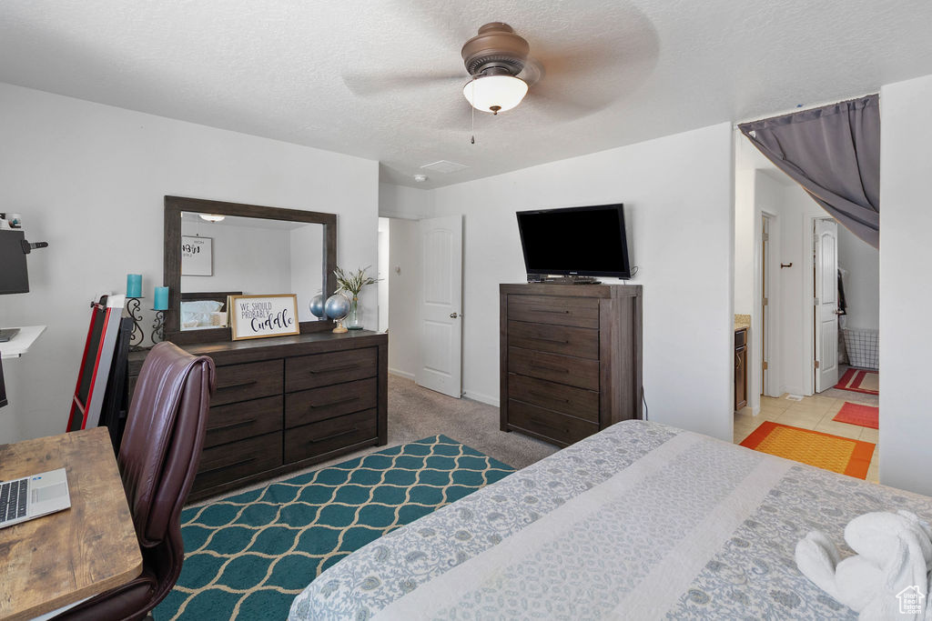 Bedroom with an office area, a textured ceiling, a ceiling fan, and carpet floors