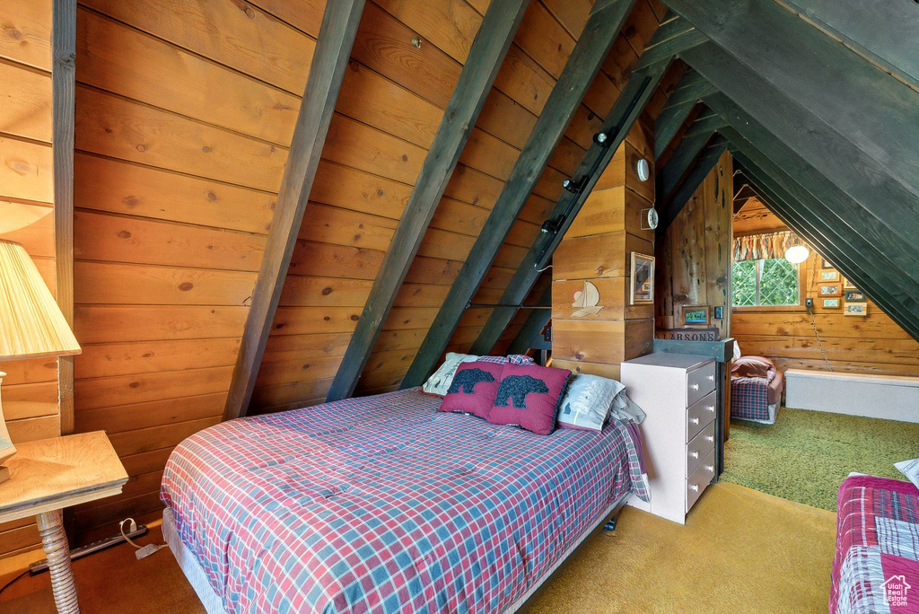 Carpeted bedroom with wood walls and vaulted ceiling