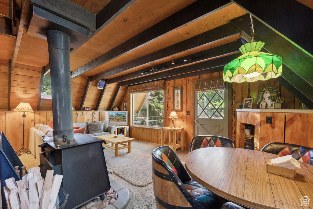 Dining space with a wood stove, wood walls, and carpet flooring
