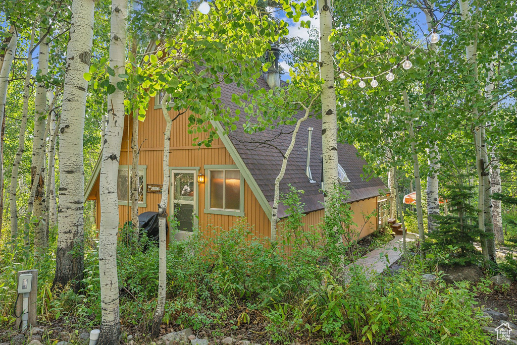 View of side of home featuring roof with shingles