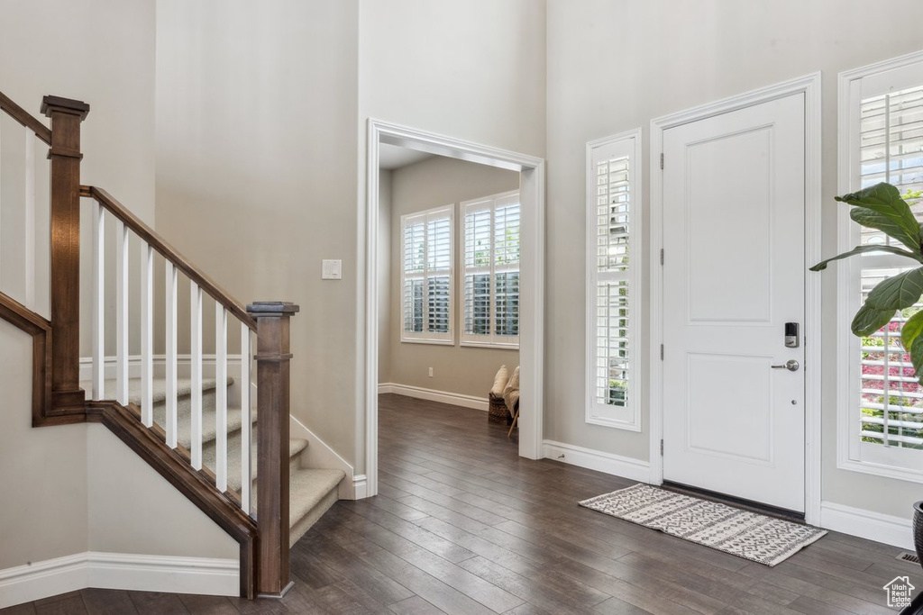 Entryway featuring plenty of natural light, stairway, dark wood-style flooring, and a towering ceiling
