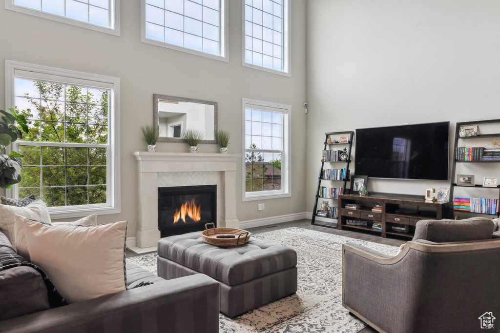 Living room with a towering ceiling, a tile fireplace, plenty of natural light, and baseboards