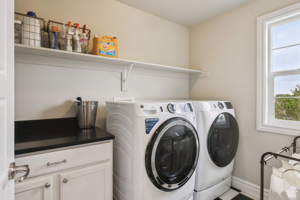 Clothes washing area featuring independent washer and dryer, cabinet space, and baseboards