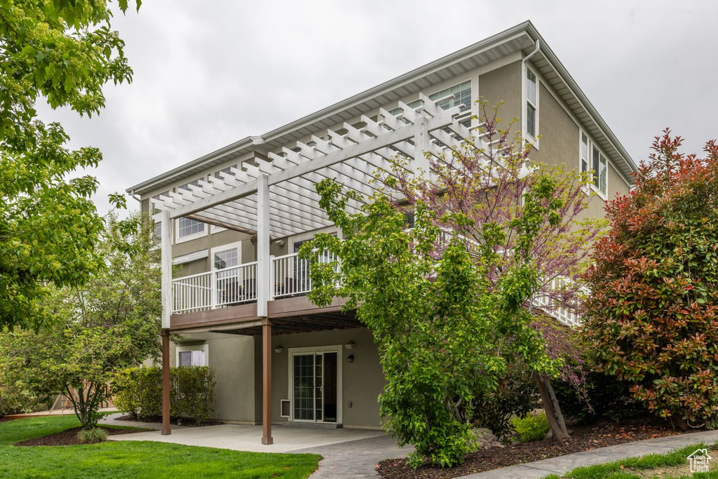 Back of house featuring stucco siding, a patio area, a pergola, and a lawn