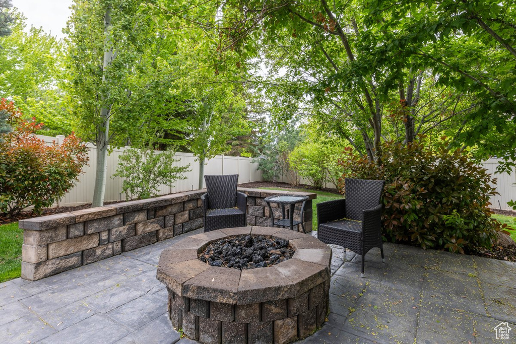 View of patio with an outdoor fire pit and a fenced backyard