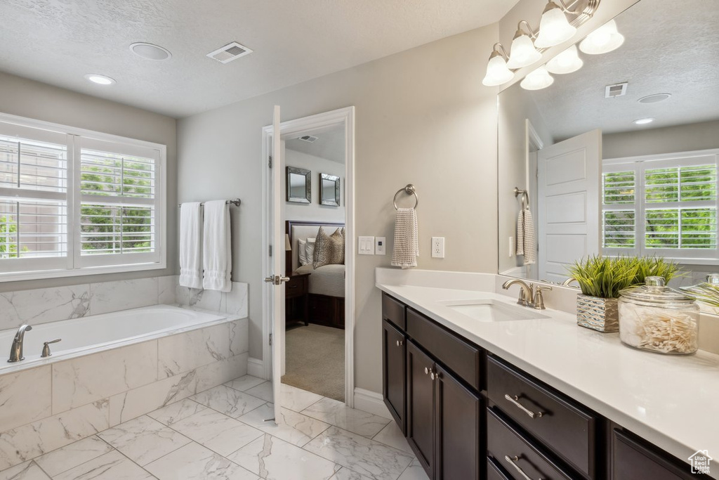 Ensuite bathroom featuring vanity, a bath, marble finish floors, and baseboards