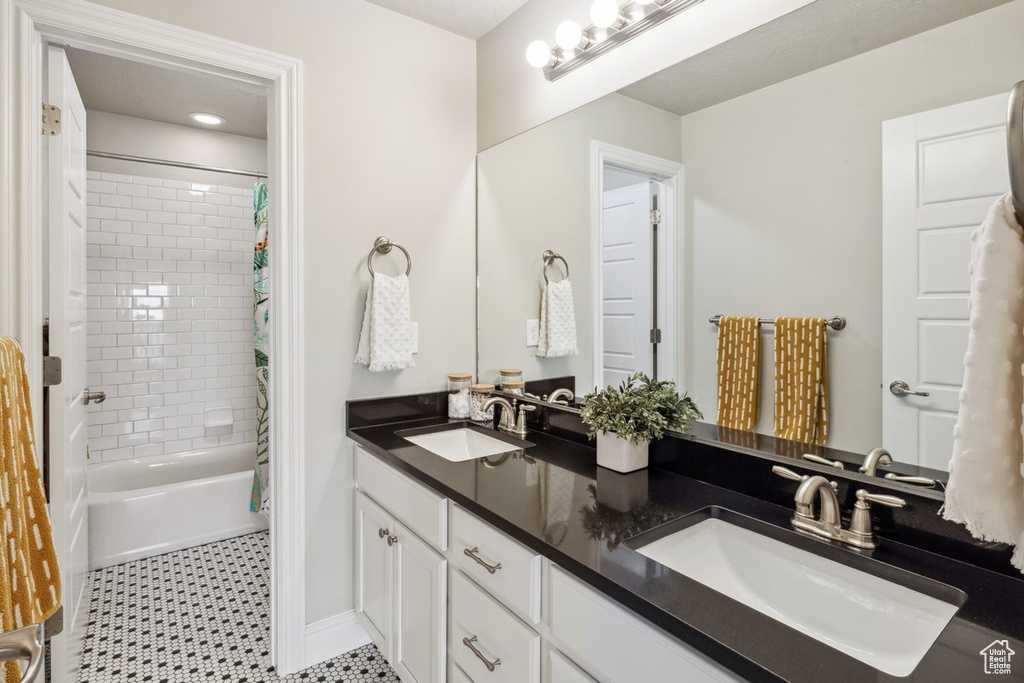 Full bath with double vanity, shower / bath combination with curtain, and baseboards