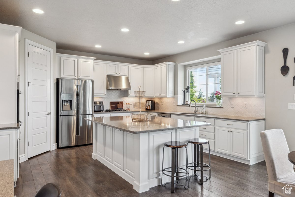Kitchen featuring stainless steel refrigerator with ice dispenser, under cabinet range hood, a sink, dark wood-style floors, and recessed lighting