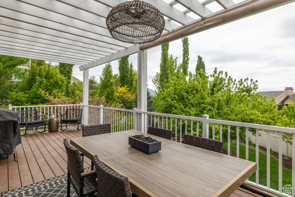 Wooden deck with a pergola, outdoor dining area, an outdoor fire pit, and a grill