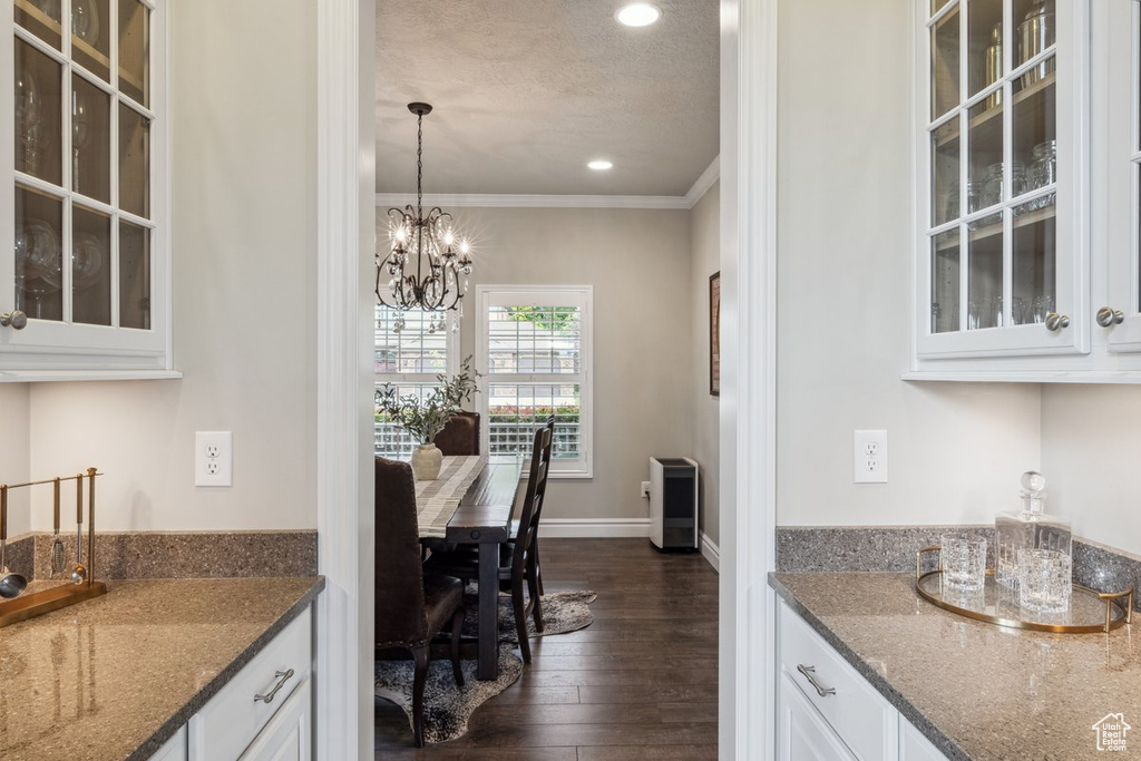 Bar with crown molding, dark wood-style flooring, a chandelier, recessed lighting, and decorative light fixtures