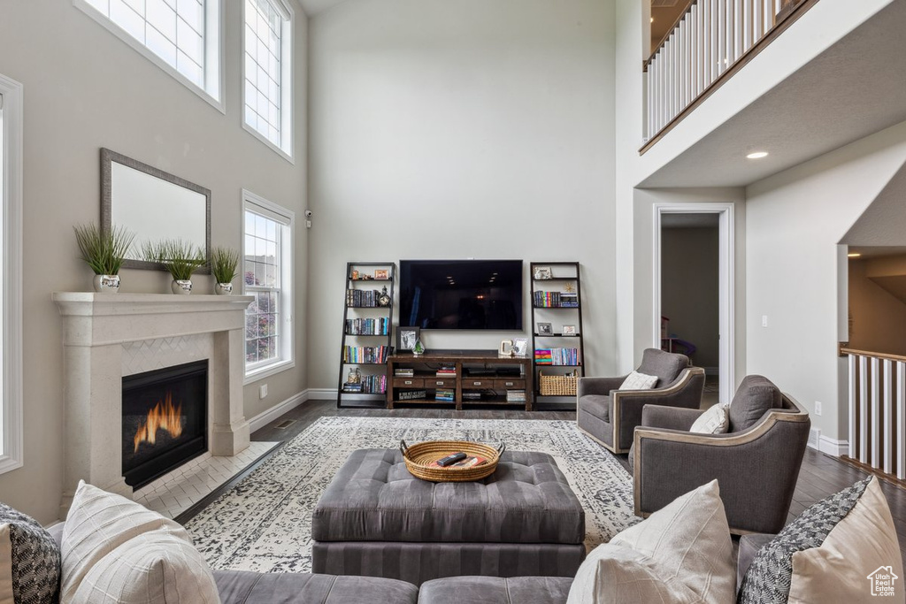 Living room featuring a high ceiling, wood finished floors, baseboards, and a fireplace with flush hearth