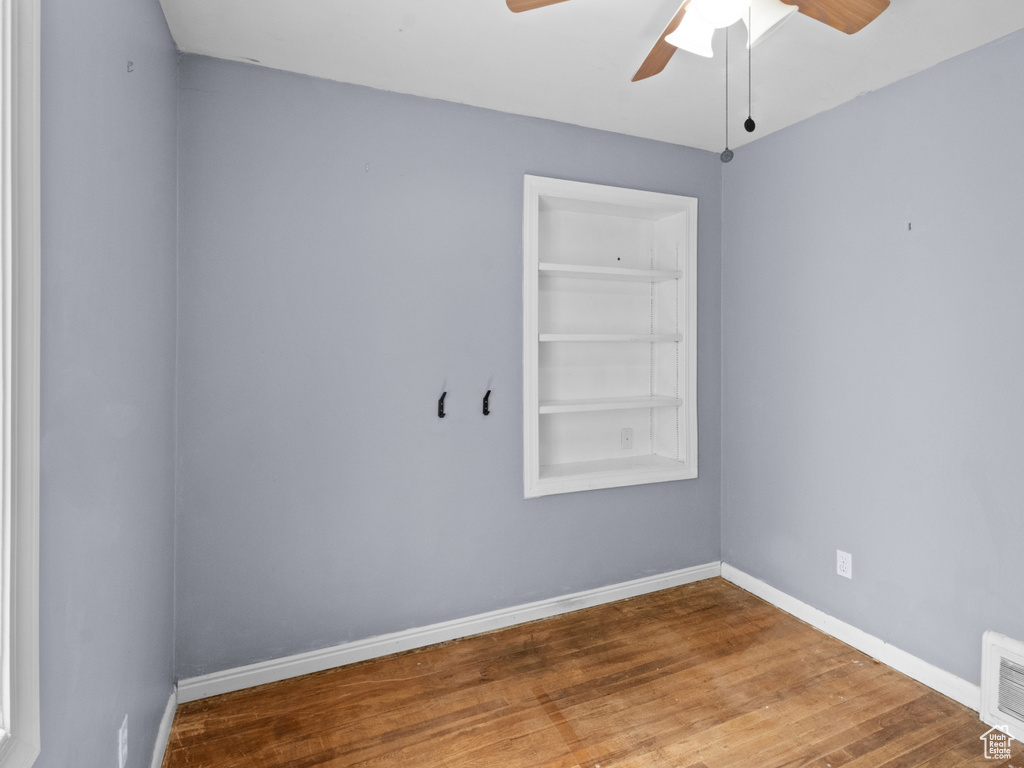 Spare room with ceiling fan, wood finished floors, and baseboards