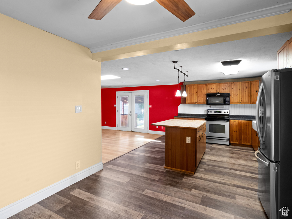 Kitchen with appliances with stainless steel finishes, a center island, crown molding, dark wood-style flooring, and ceiling fan