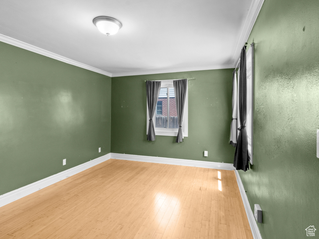 Unfurnished room featuring wood finished floors, crown molding, and baseboards