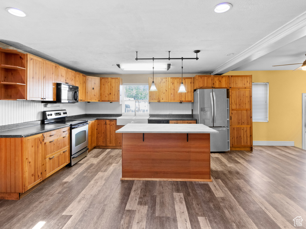 Kitchen with appliances with stainless steel finishes, wood finished floors, open shelves, a center island, and a sink
