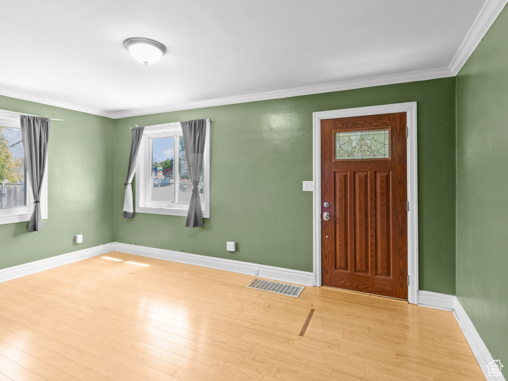 Foyer entrance featuring plenty of natural light, wood finished floors, ornamental molding, and baseboards