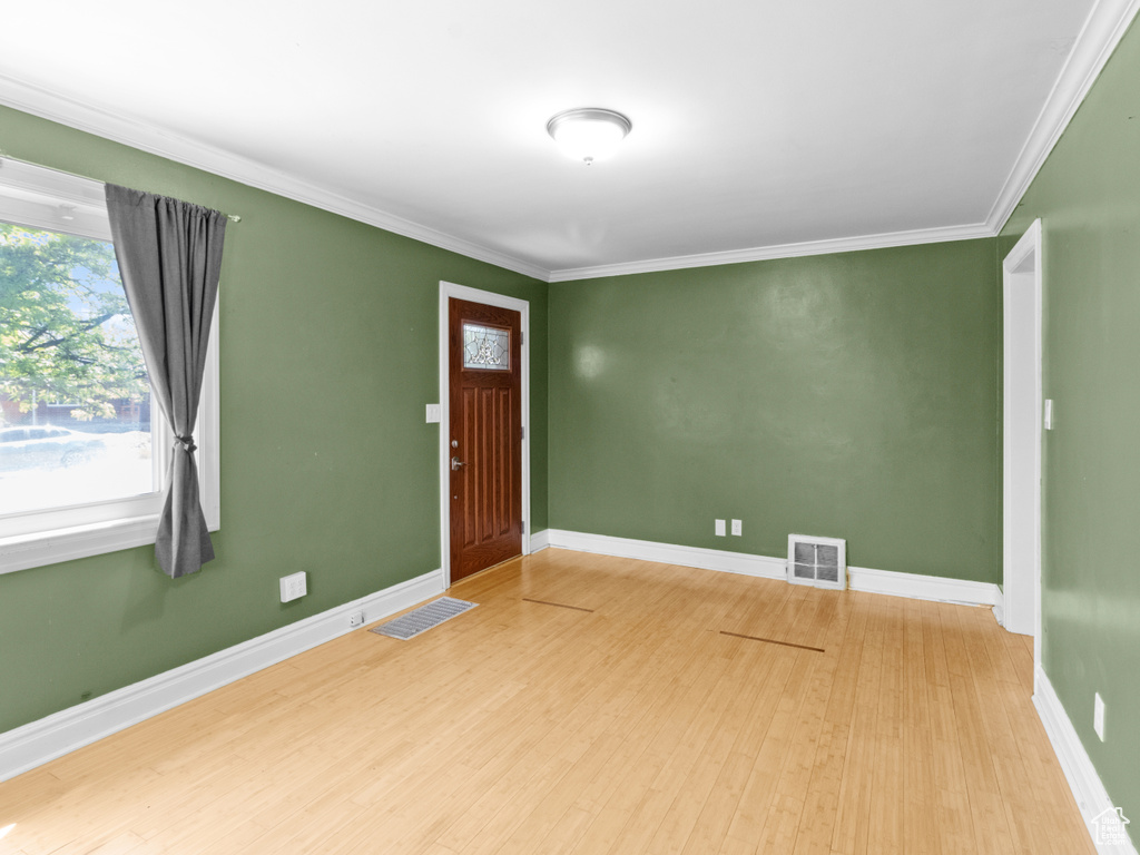 Empty room with wood finished floors, ornamental molding, and baseboards
