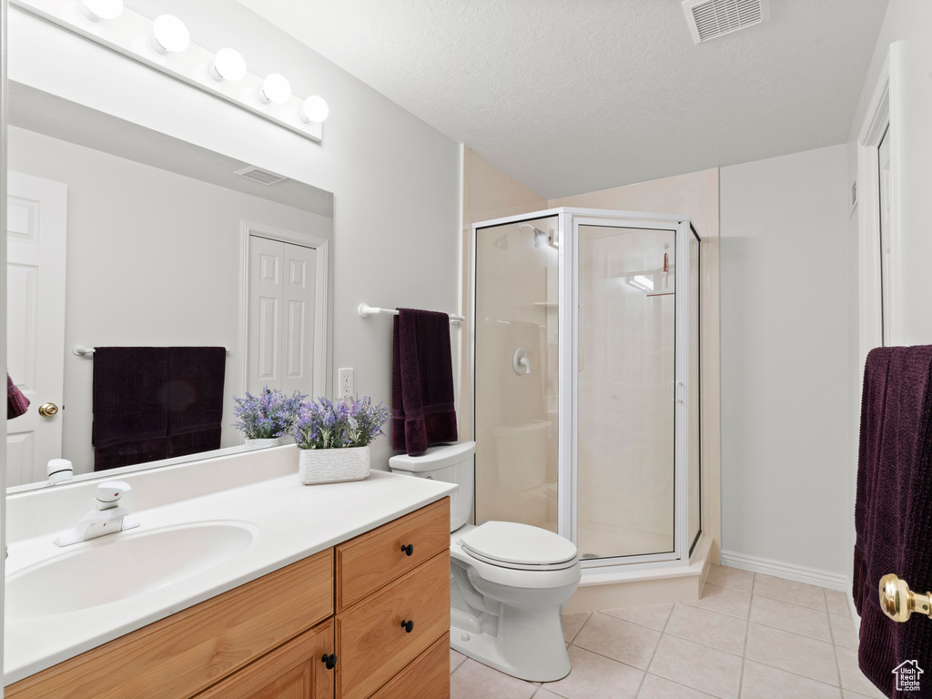Bathroom with tile patterned floors, a stall shower, vanity, and toilet