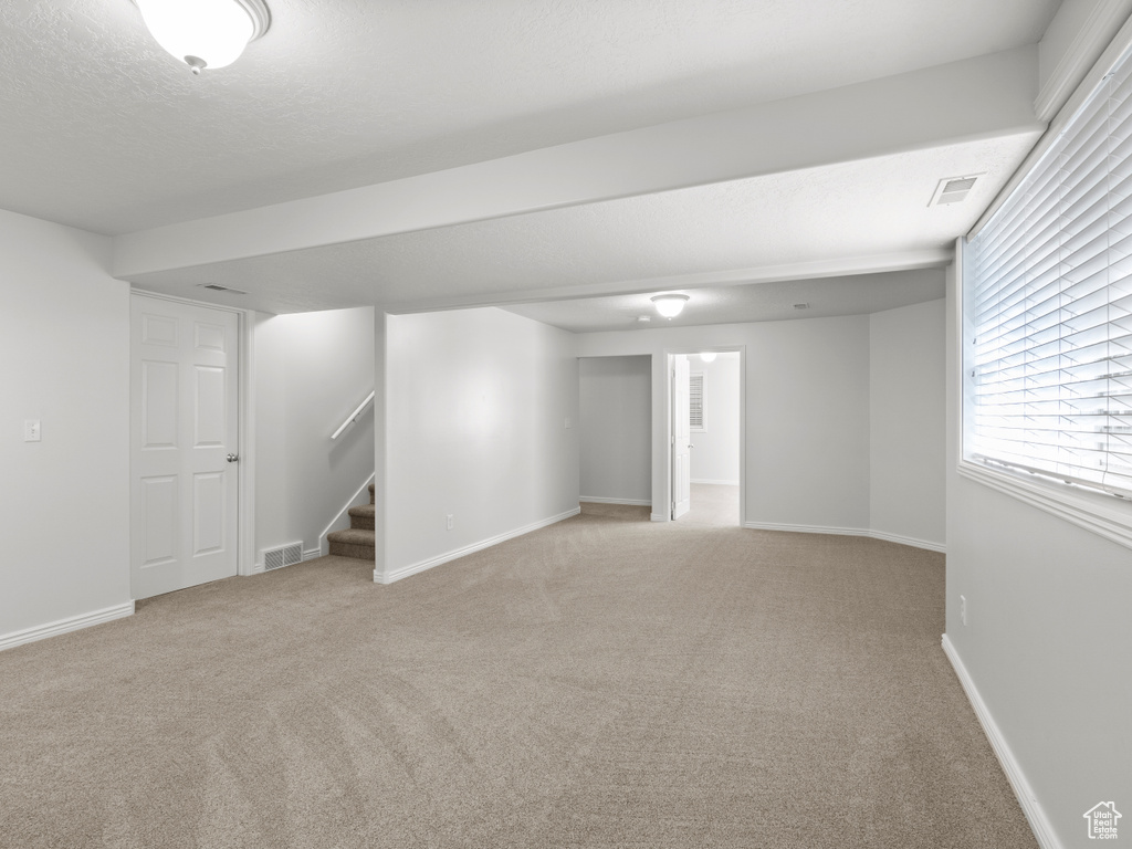 Basement featuring carpet, stairs, and baseboards