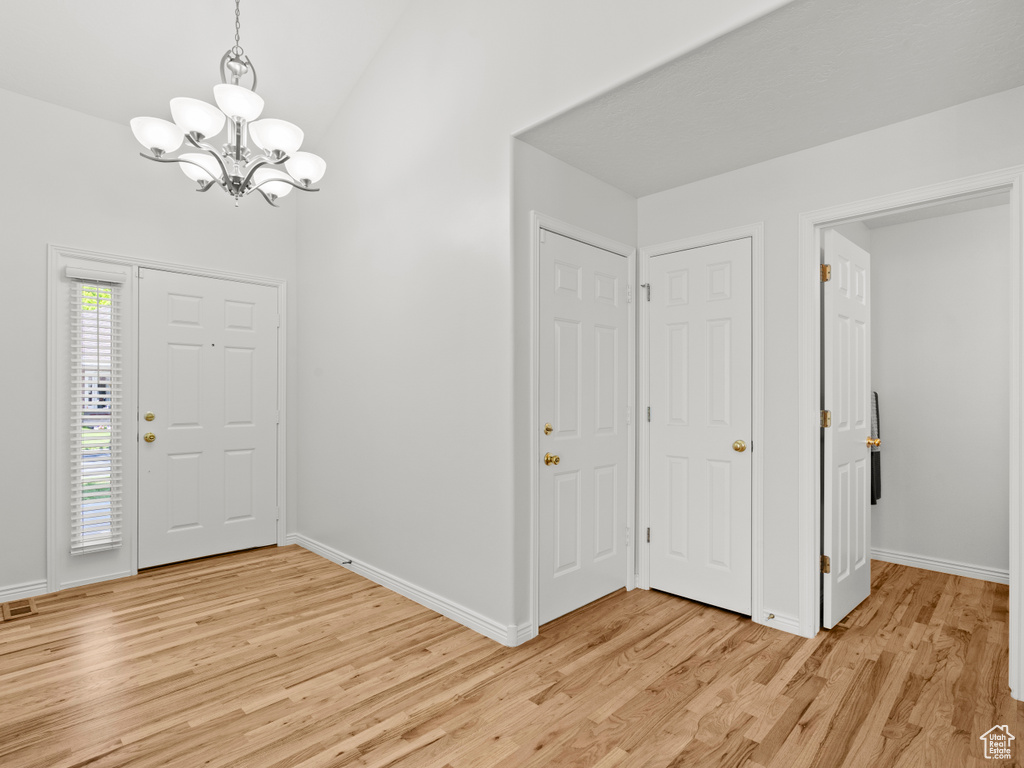 Entrance foyer featuring a chandelier, light wood-style floors, and baseboards