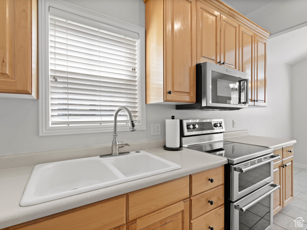 Kitchen with stainless steel appliances, a sink, healthy amount of natural light, and light tile patterned floors