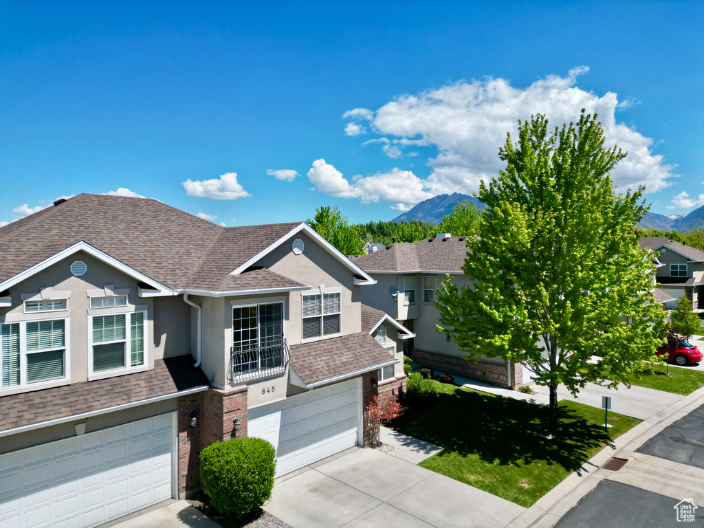 View of front of property featuring an attached garage, roof with shingles, a mountain view, and concrete driveway