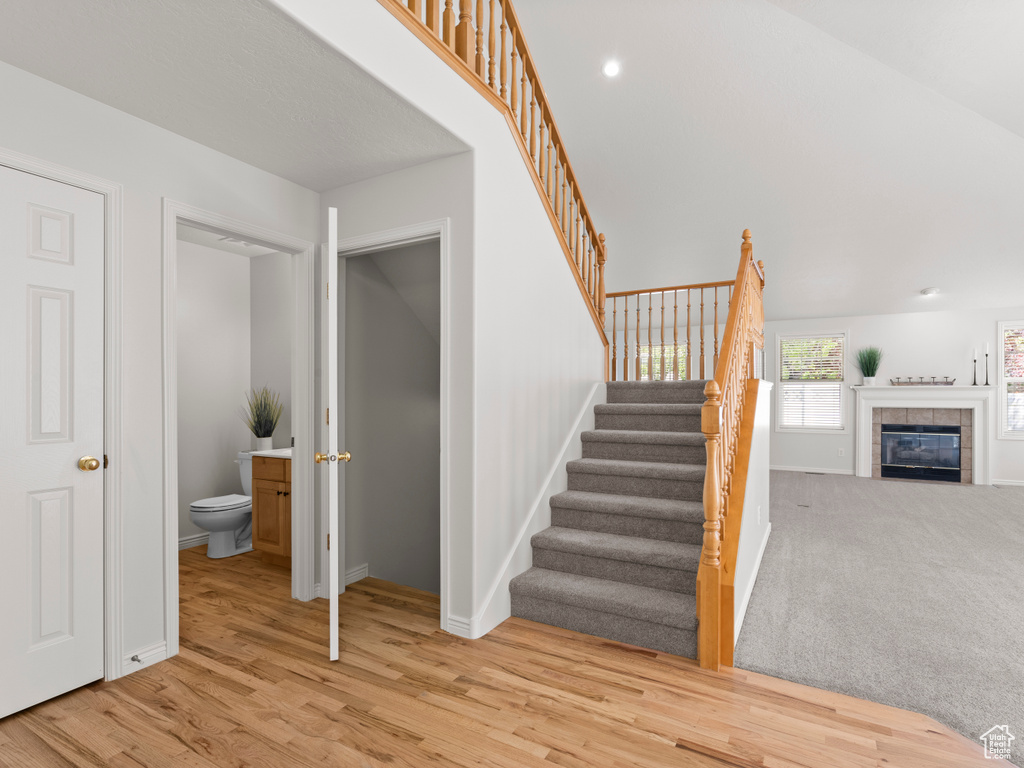 Staircase featuring wood finished floors, baseboards, and a fireplace