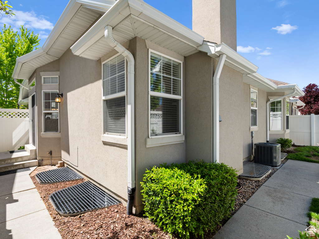 View of property exterior with fence, stucco siding, and central air condition unit