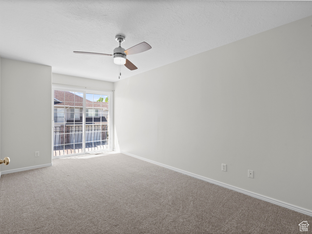 Carpeted empty room with ceiling fan and baseboards