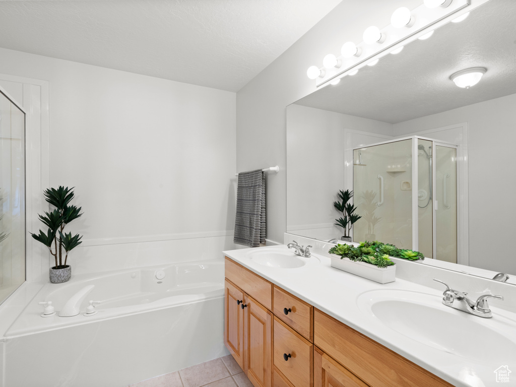 Bathroom featuring a shower stall, double vanity, tile patterned floors, and a bath