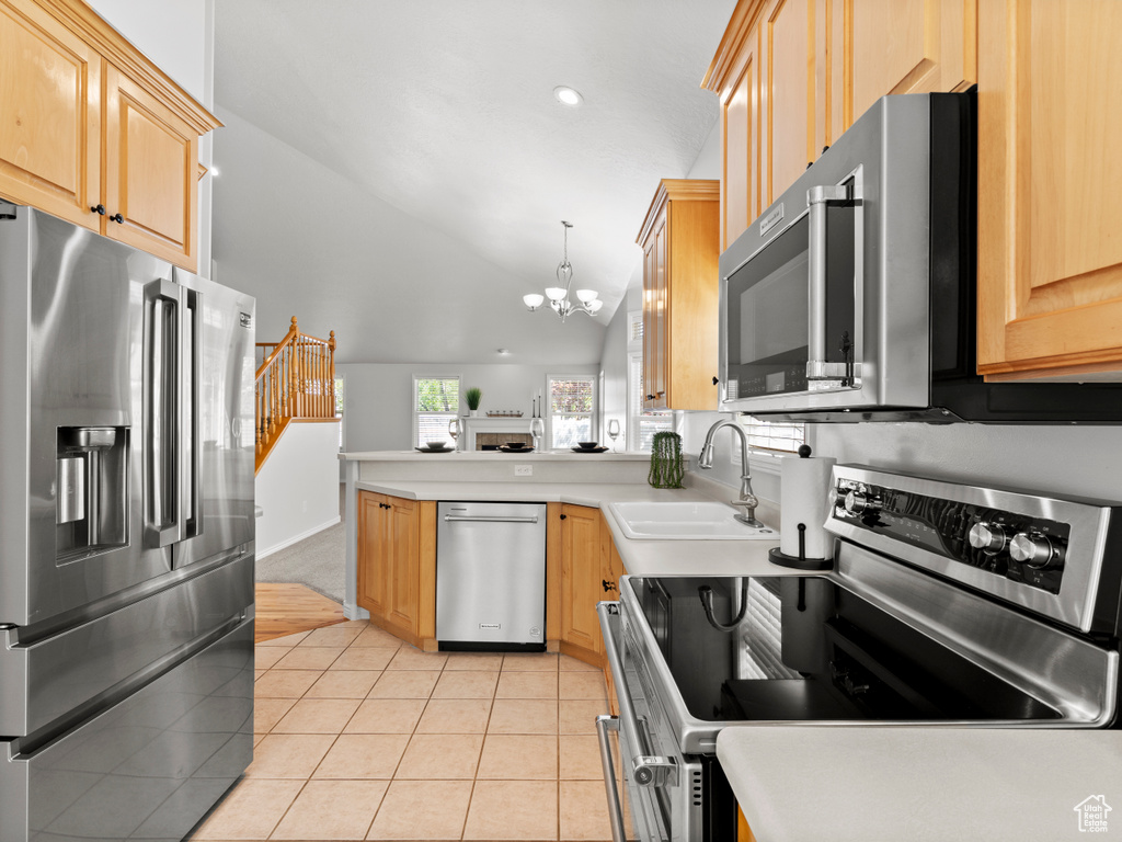 Kitchen featuring appliances with stainless steel finishes, a sink, a chandelier, light tile patterned flooring, and a peninsula