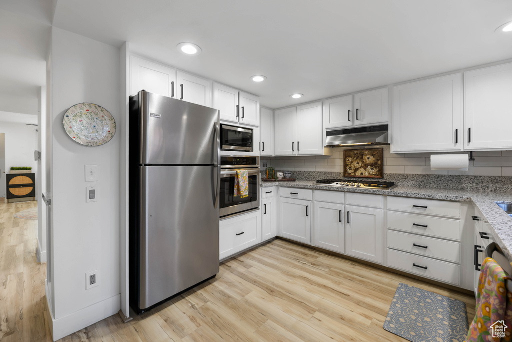 Kitchen featuring appliances with stainless steel finishes, under cabinet range hood, light wood finished floors, backsplash, and recessed lighting