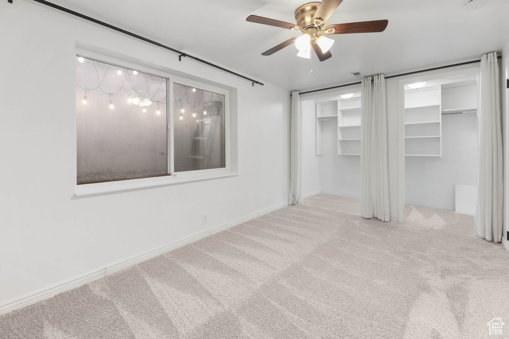 Unfurnished bedroom with carpet, baseboards, multiple closets, and ceiling fan