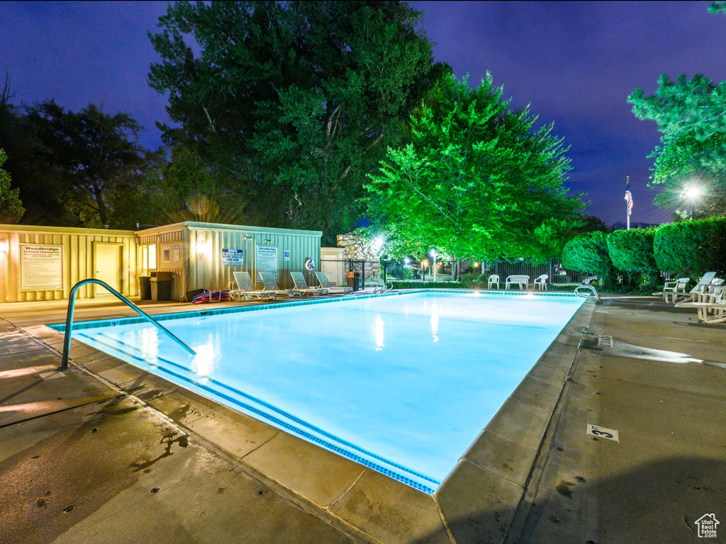 Pool at twilight featuring a community pool, fence, and a patio area