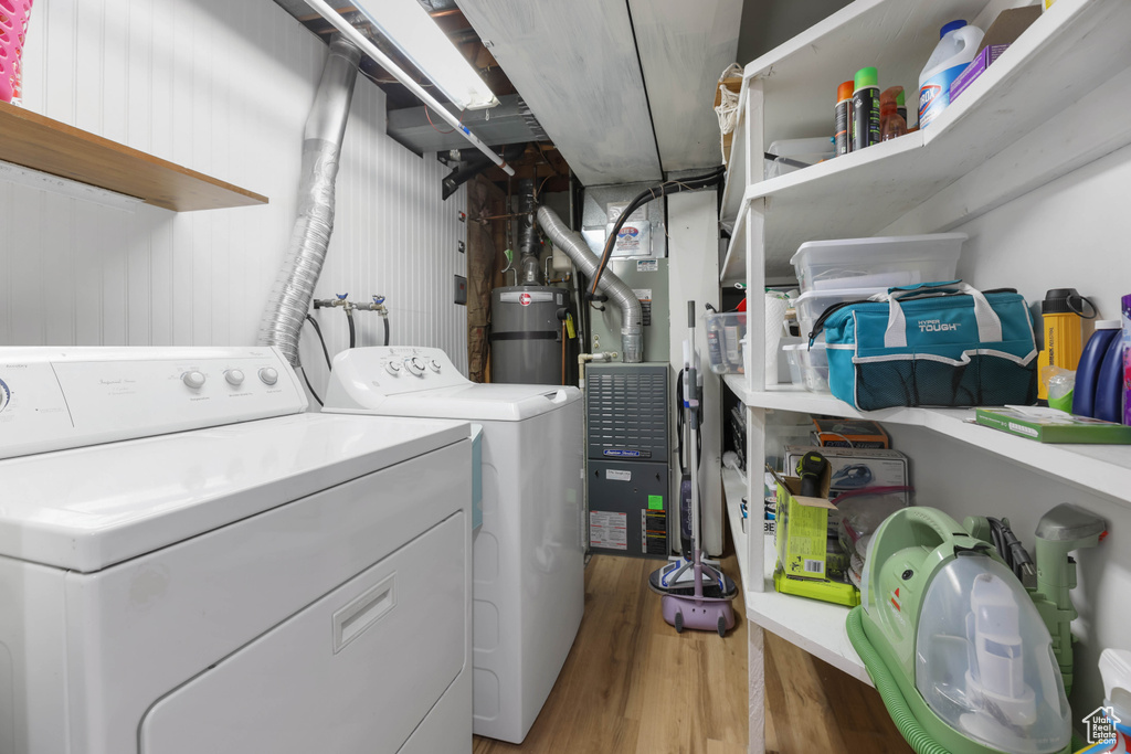 Laundry room featuring water heater, separate washer and dryer, light wood-style floors, and heating unit