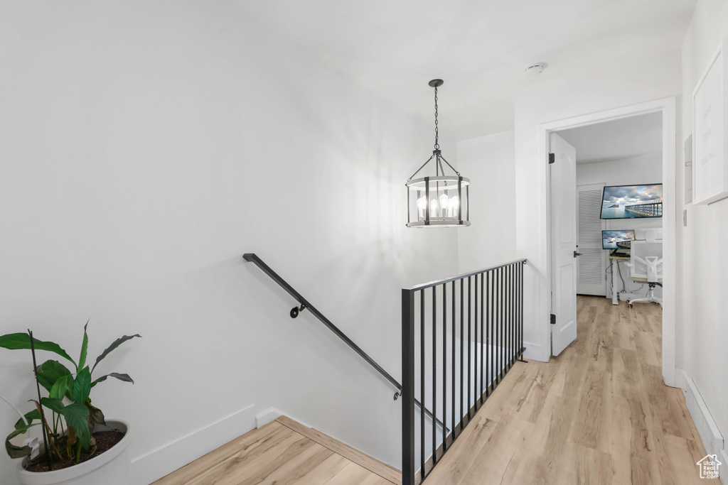 Staircase featuring wood finished floors, baseboards, and a chandelier