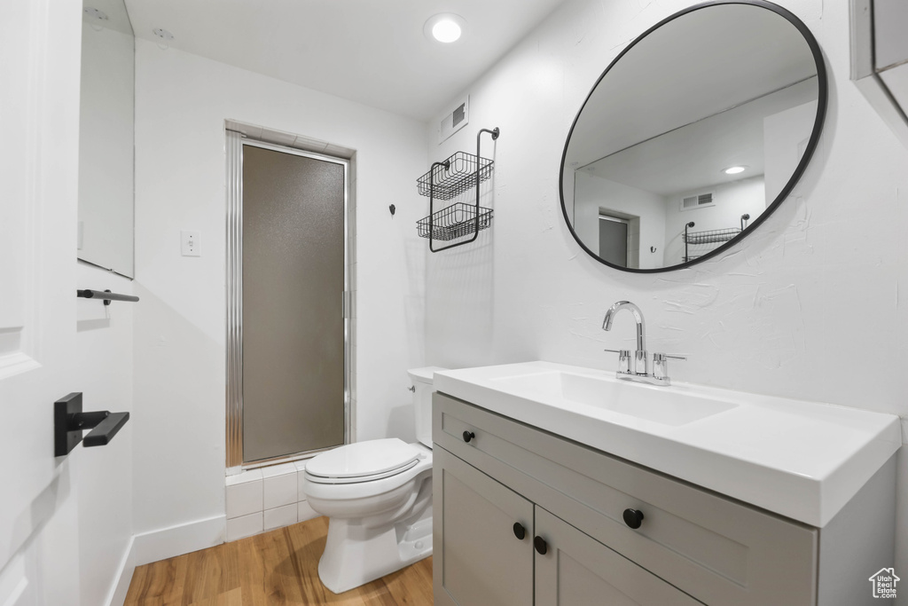 Full bathroom with wood finished floors, a shower stall, toilet, and vanity