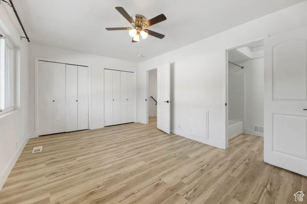 Unfurnished bedroom with light wood finished floors, two closets, baseboards, and ceiling fan