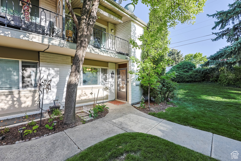 Entrance to property featuring a balcony and a yard