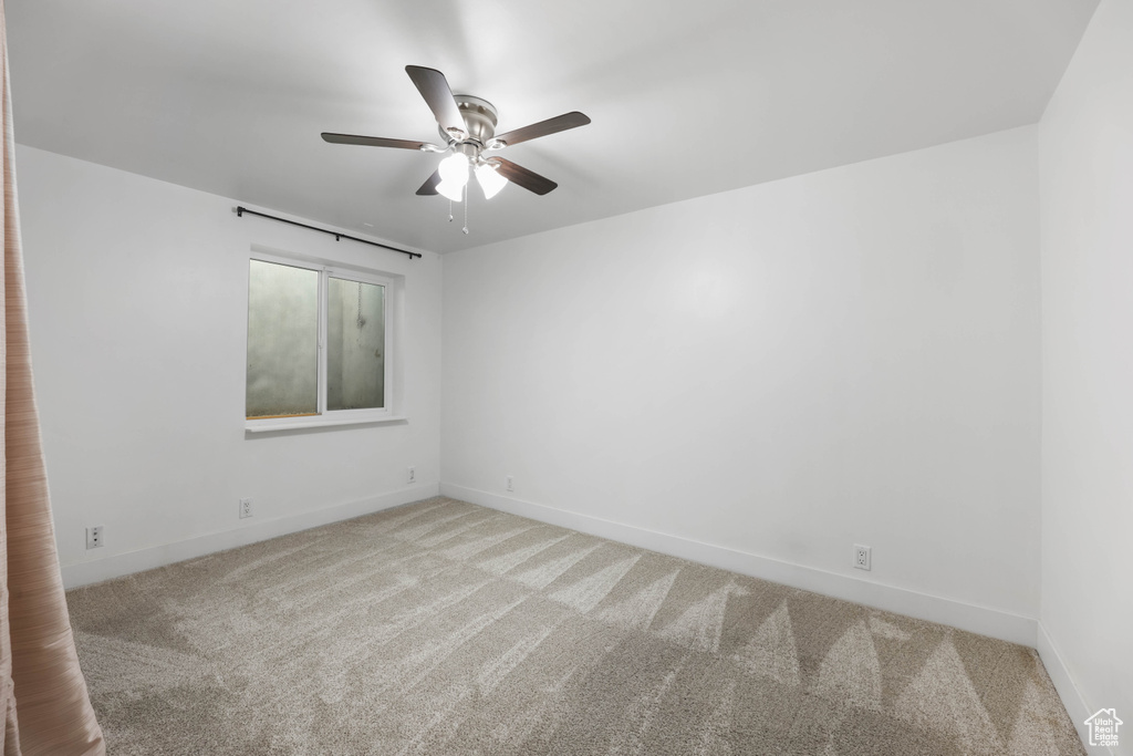 Carpeted spare room featuring ceiling fan and baseboards