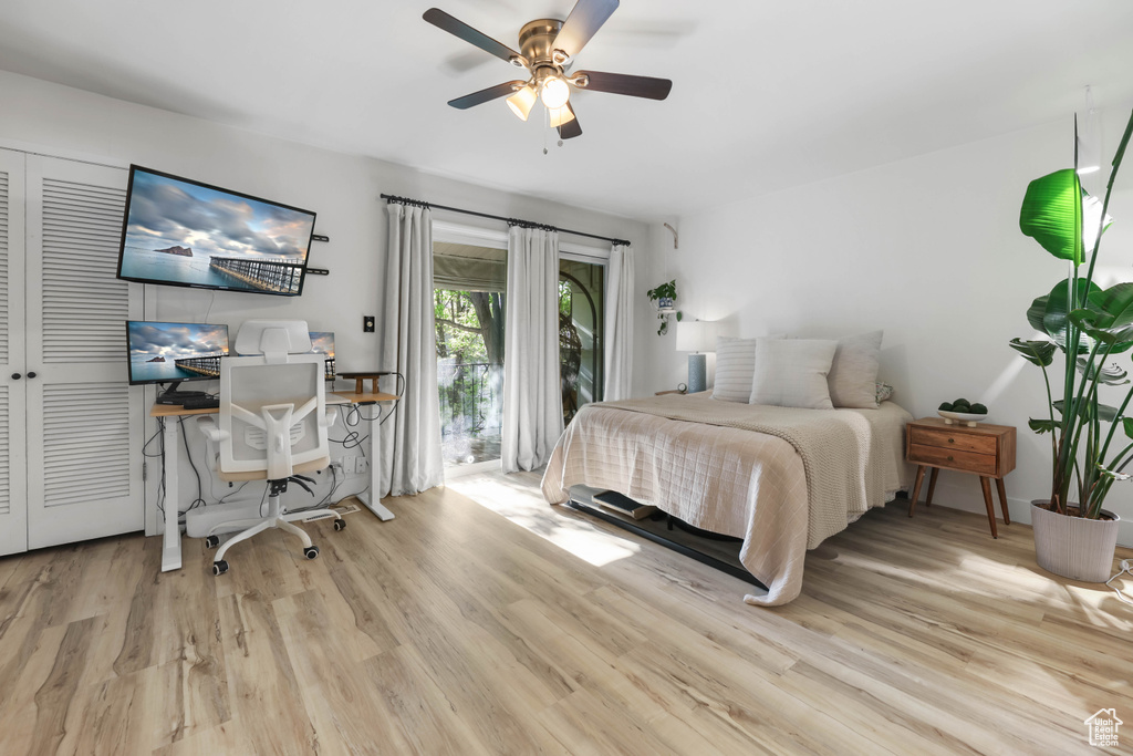 Bedroom with wood finished floors, access to exterior, an office area, and a ceiling fan