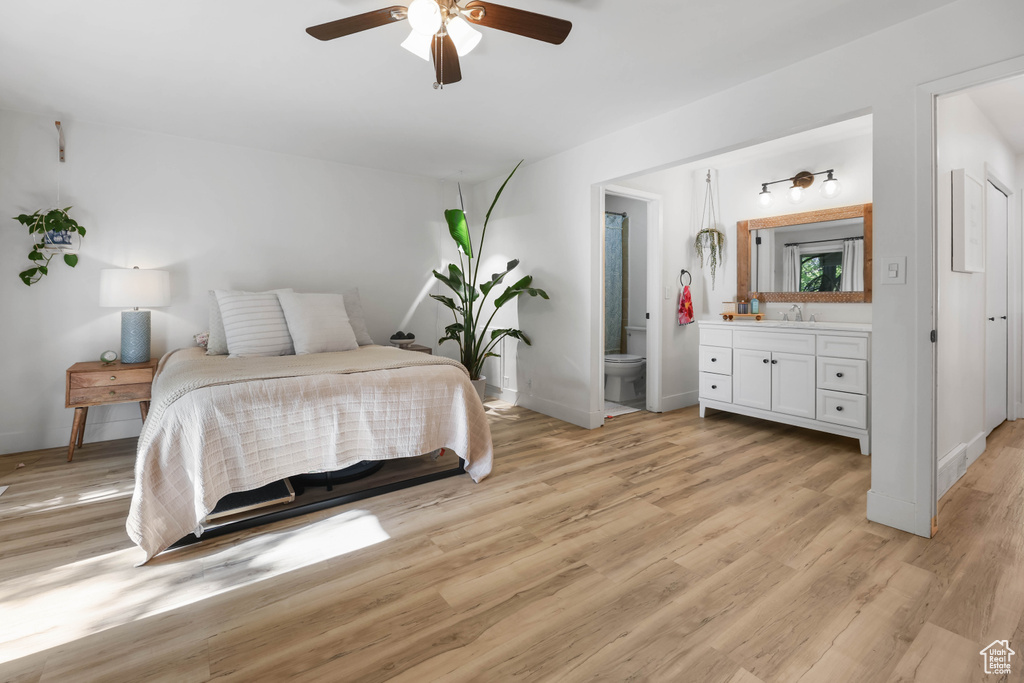Bedroom with a sink, light wood-type flooring, ensuite bathroom, and baseboards