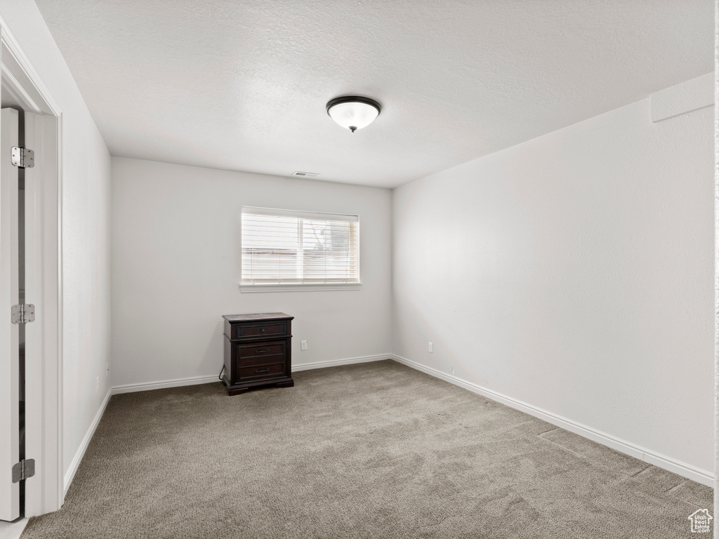 Carpeted spare room featuring baseboards