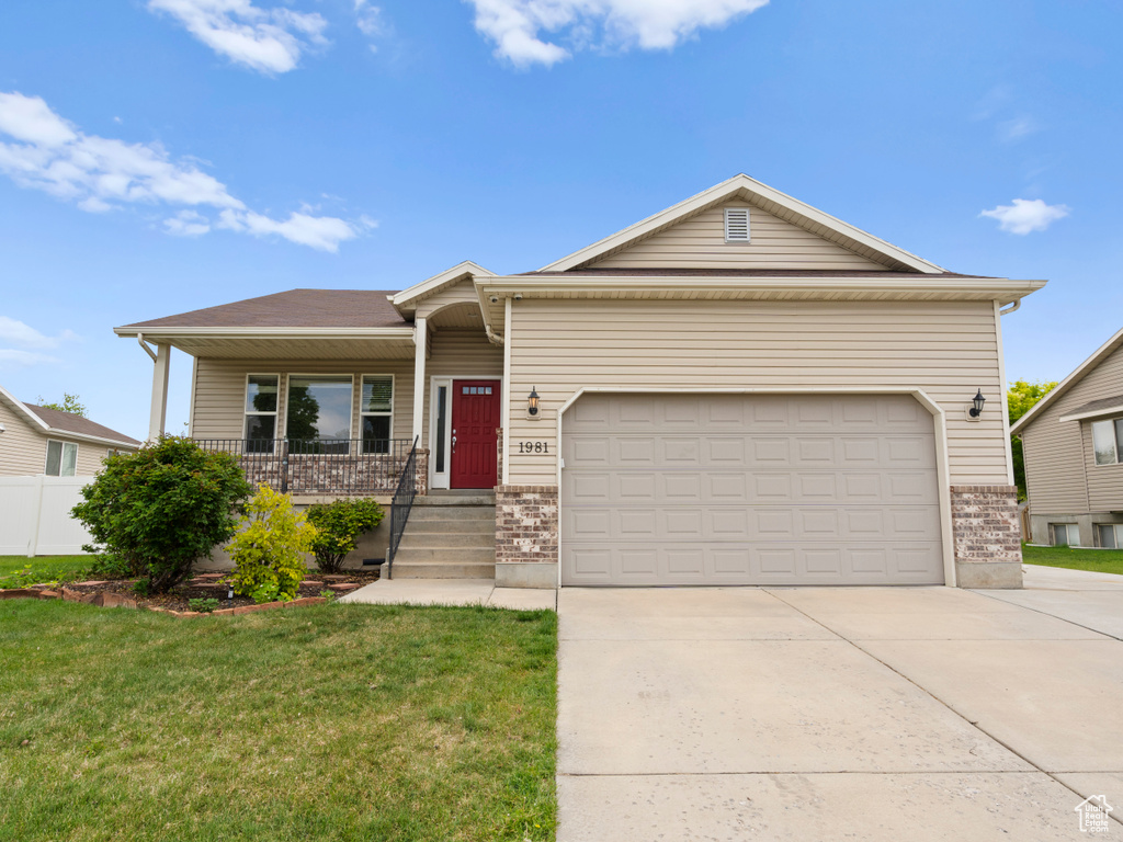 View of front of property with concrete driveway, brick siding, a porch, a garage, and a front yard