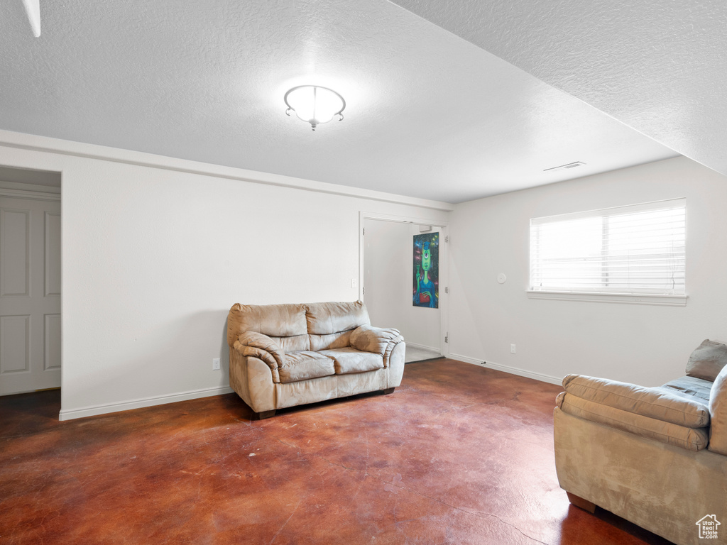 Living area featuring baseboards and a textured ceiling