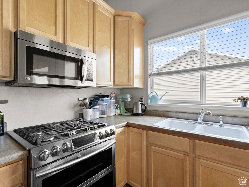 Kitchen featuring stainless steel appliances, a sink, and light brown cabinets