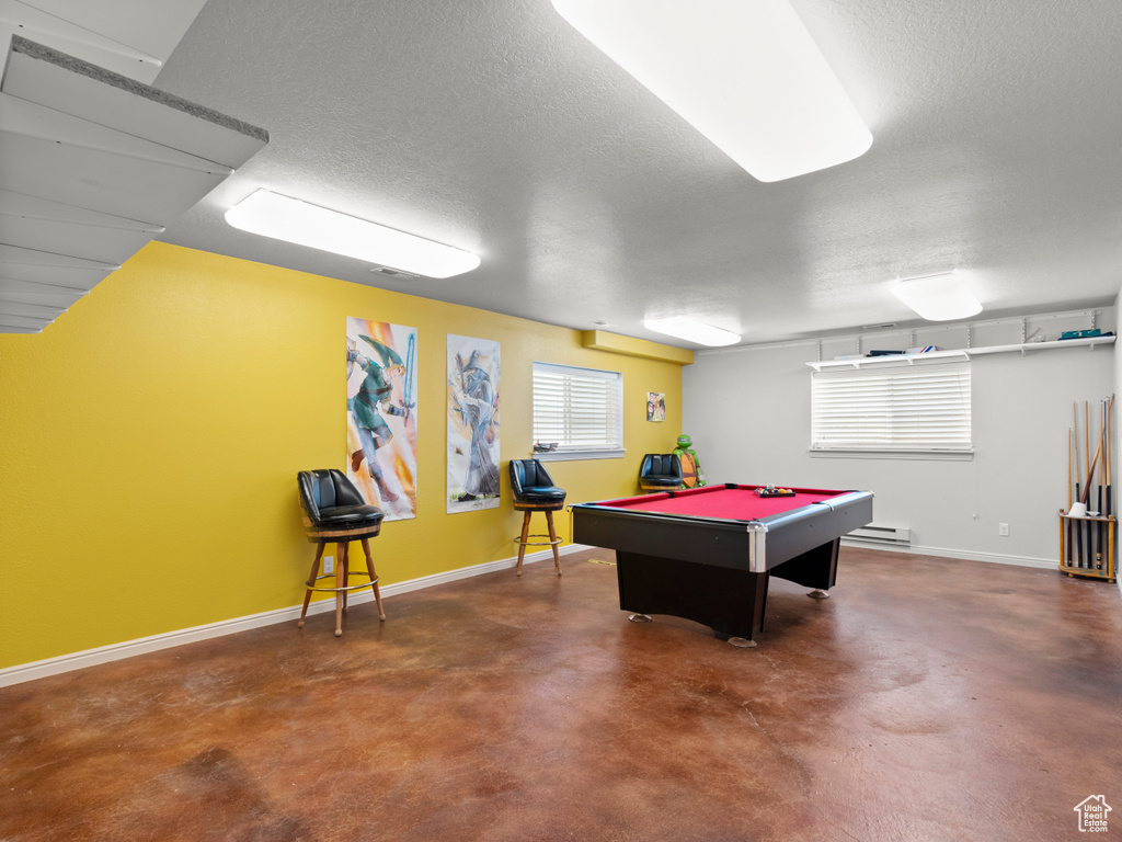 Rec room with concrete floors, billiards table, baseboards, baseboard heating, and a textured ceiling